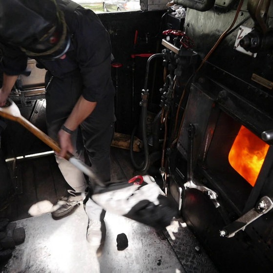 Eisenmitarbeiter befeuert Dampflokomotive