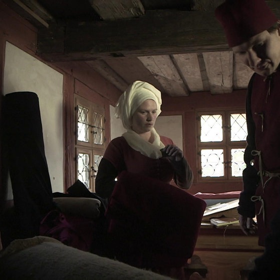 Nachgestellte Szene: Kaufmann prüft Stoffe