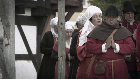 Männer und Frauen mit gefalteten Händen auf einer Straße.