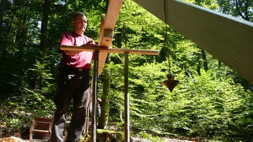Ein Mann bei der Höhenvermessung mit einem römischen Messaparat. (Foto: SWR)