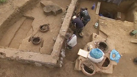 Mehrere Menschen arbeiten in einer archäologischen Ausgrabungsstätte.