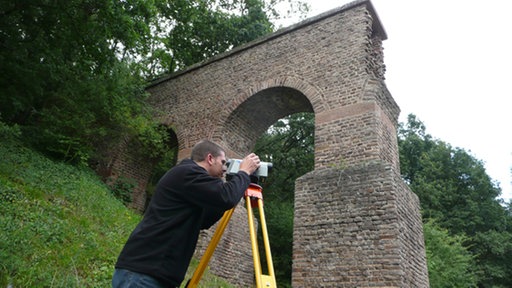 Ein Mann schaut durch ein Messinstrument.