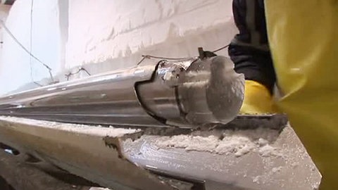 Ein Bohrkern aus dem Grönlandeis, noch in einer langen Metallröhre.