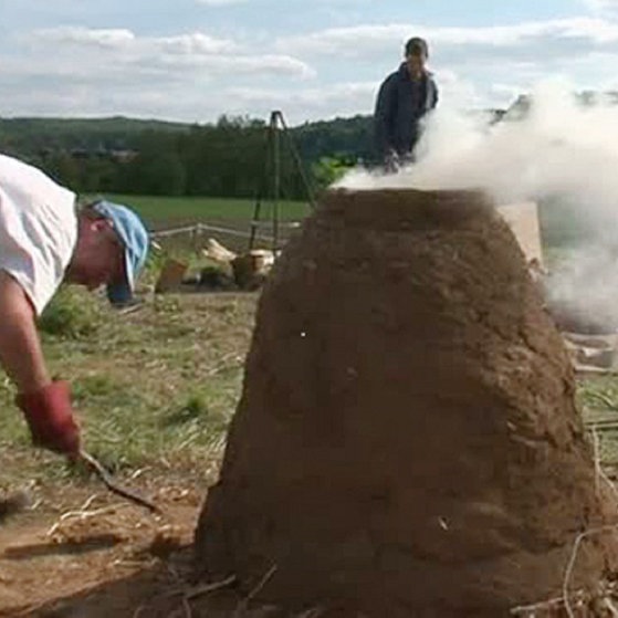 Ein Mann arbeitet an einem römischen Rennofen.