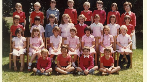 Ein Klassenfoto: Die Schüler tragen rote Schuluniformen und sind in vier Reihen aufgestellt