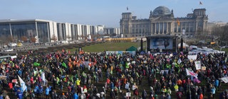 Menschen versammeln sich vor dem Reichstag in Berlin. Wie funktioniert unsere Demokratie? Wie geht Zusammenleben in unserer Gesellschaft? 