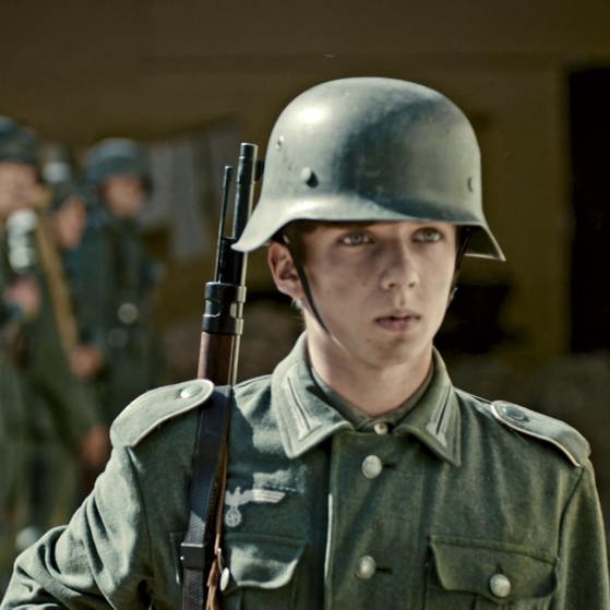 Jugendlicher in Uniform und mit Waffe. (Foto: SWR, LOOKS Film und Toto Studio – Screenshot aus der Sendung)