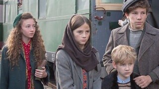 Vier Kinder stehen vor einem Zug.