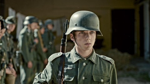 Jugendlicher in Uniform und mit Waffe.