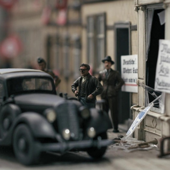 Auto und drei Männer vor einem verwüsteten Laden.