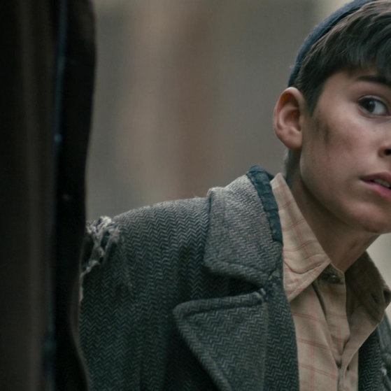 Junge mit Käppi und zerschlissener Jacke schaut ängstlich.