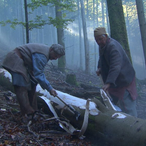 Zwei Holzfäller entrinden einen am Boden liegenden Baumstamm. (Foto: SWR - Screenshot aus der Sendung)