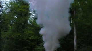 Kohlemeiler, aus dem Flammen und Rauch entweichen.