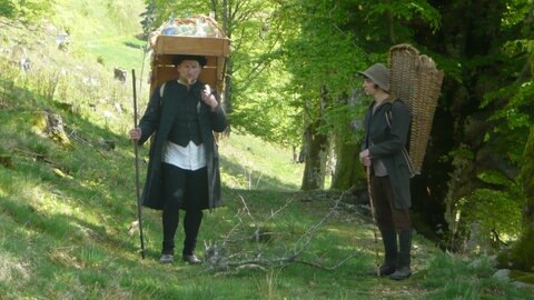 Glasträger mit Holzgestell mit Glaswaren auf dem Rücken; sein Begleiter trägt einen Korb auf dem Rücken.
