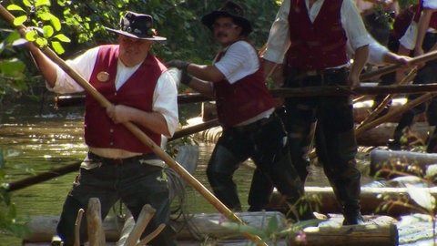 Mehrere Männer steuern und treiben ein Boot an.