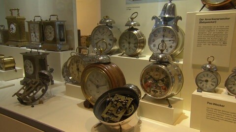 Verschiedene eckige und runde Wecker in Vitrine