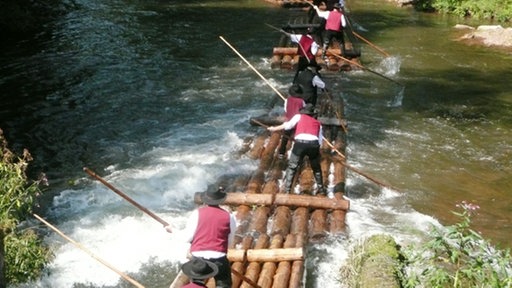 Mehrere Flößer auf bewegtem Fluss