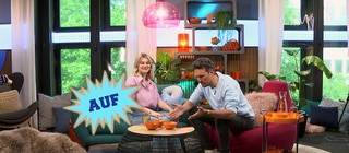 Host Gero sitzt mit einer Frau im Studio an einem Tisch, eingeblendet das Wort "auf"