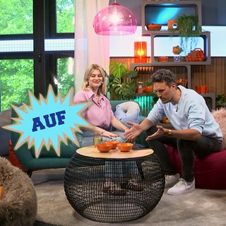 Host Gero sitzt mit einer Frau im Studio an einem Tisch, eingeblendet das Wort "auf"