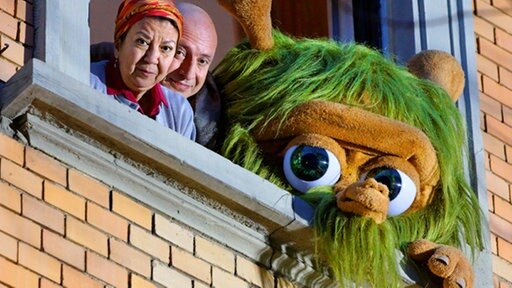 Zinell, Eine Frau und ein Mann schauen aus einem Fenster.
