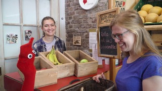 Esther und die rote Socke werden am Tresen des Lebensmittelgeschäftes bedient.