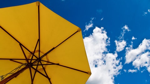 Sonnenschirm im blauen Himmel: Das Ozonloch lässt die gefährliche UV-Strahlung der Sonne auf die Erde.