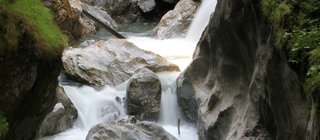 Der Oberlauf eines Bachs fließt zwischen Felswänden hindurch.