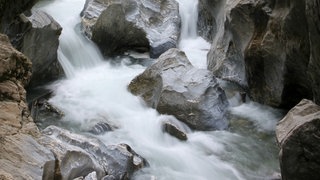 Der Oberlauf eines Bachs fließt zwischen Felswänden hindurch.