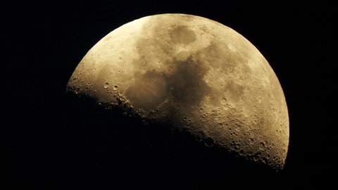 Der Mond halb von der Sonne angestrahlt. Er hat eine trockene Oberfläche ohne Wasser - anders als die Erde.