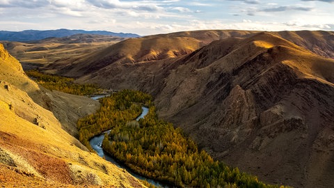 Ausblick auf ein Tal, durch das ein Fluss fließt. Das Wasser gräbt sich mit der Zeit immer tiefer in den Untergrund ein.