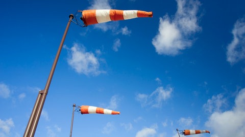Rot-weißer Windsack am blauen Himmel: Wie entsteht Wind? Was macht die Luft in der Erdatmosphäre?
