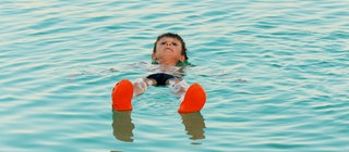 Ein Junge lässt sich auf der Wasseroberfläche treiben. Das Tote Meer ist so salzig, dass man auf dem Wasser liegen kann.