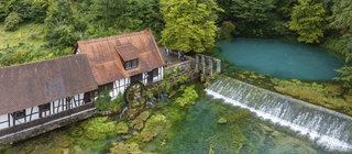 Auf der schwäbischen Alb versickert Regenwasser im Boden. An einer Quelle namens Blautopf tritt das Grundwasser wieder aus. 