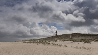 Der Strand von Sylt, im Hintergrund ein Leuchtturm. Würde der Mensch nichts unternehmen, dann würde die Insel im Laufe der Zeit vom Meer weggespült werden.