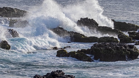 Meer und Ozeane - Brandung am Felsstrand: Wasser spritzt gegen die Steine am Ufer.