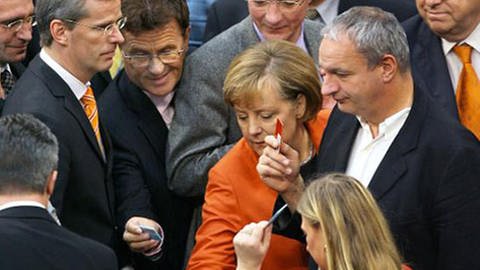 Im Mittelpunkt Bundeskanzlerin Merkel umgeben von anderen Abgeordneten bei der Stimmabgabe (Foto: dpa)