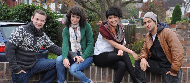 Vier junge Menschen sitzen auf einer Mauer über dem Schild "Silverleaf Gardens". (Foto: WDR/footstep production)