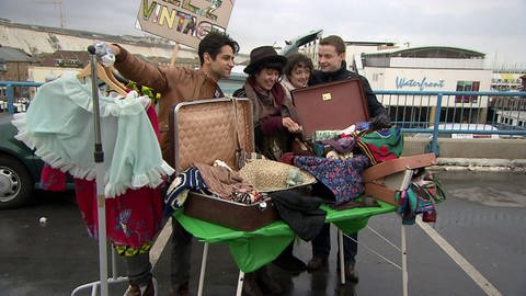 Vier junge Leute stehen an einem Stand auf dem Flohmarkt, vor ihnen viele Kleidungsstücke. (Foto: WDR/ Footstep production)