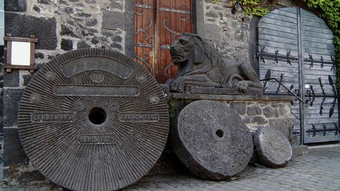 Mühlsteine lehnen an einer Wand.