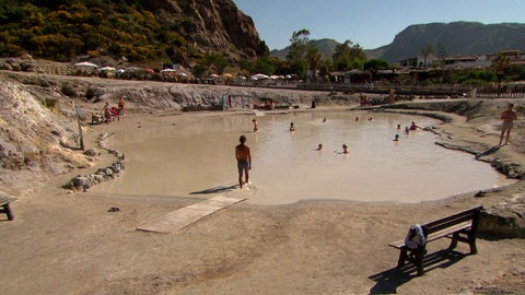 Menschen baden in schlammigem Gewässer.