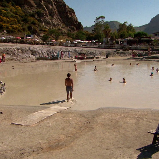 Menschen baden in schlammigem Gewässer.