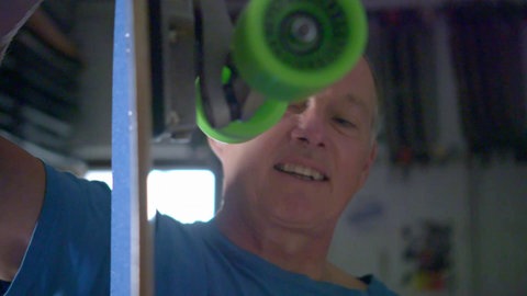 Martin Sammet hält ein Surfskate senkrecht.