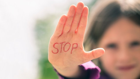Mädchen streckt Hand aus, auf der Stop steht.