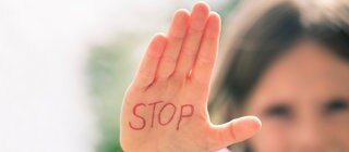 Mädchen streckt Hand aus, auf der Stop steht.