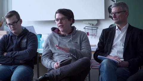 Felix sitzt in einem Klassenzimmer, neben ihm ein Lehrer und ein Schüler (Foto: SWR – Screenshot aus der Sendung)