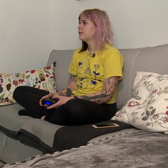 Céline sitzt auf Sofa und spielt.