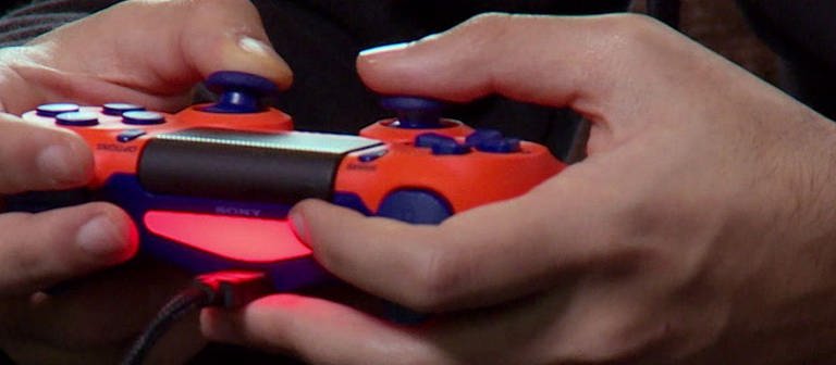 Aufnahme von Händen, die einen roten PS4 Controller halten. (Foto: SWR – Screenshot aus der Sendung)