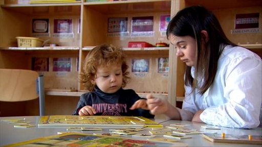 Sophie spielt mit einem Kind am Tisch.