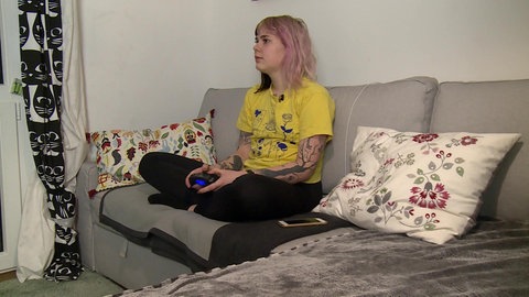Céline sitzt auf Sofa und spielt.