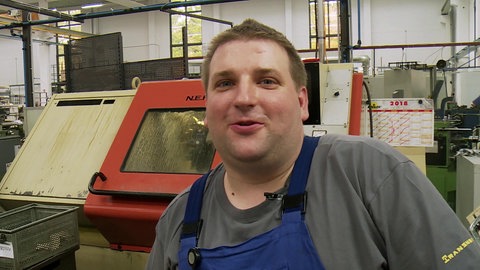 Mann steht in Werkhalle